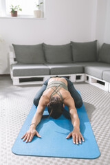 Female stretches on yoga mat in modern living room or studio to enhance flexibility and relaxation...
