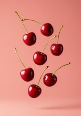 Floating ripe cherries on pink background.