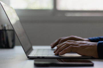 Man hand typing on laptop computer keyboard at modern desk. Remote work, freelance lifestyle, online education, digital marketing, business communication in contemporary workspace. working from home.