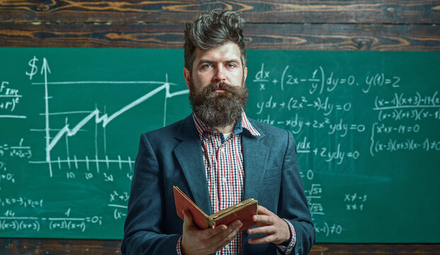 Teacher explains math at blackboard. Professor in classroom with chalkboard. University professor writes math formula. Bearded teacher. Professor teaching lesson in classroom. Professor explains math.