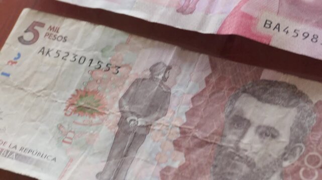 Billetes de pesos colombianos ordenados de mayor a menor denominaci&oacute;n, pasando entre ellos con un tilt down.