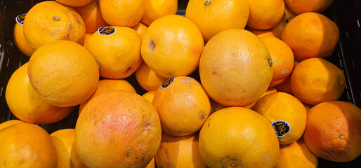 Ripe grapefruits with smooth yellow-orange skin are closely stacked in a crate, highlighting freshness and natural texture. grapefruit, citrus;