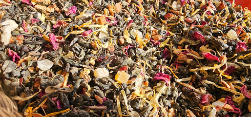 A vibrant mix of dried herbs, petals, and fruit pieces in vivid green, red, orange, and yellow...