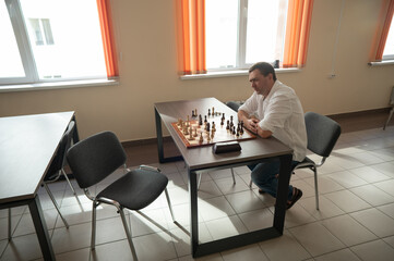 Middle aged Caucasian man playing chess. 