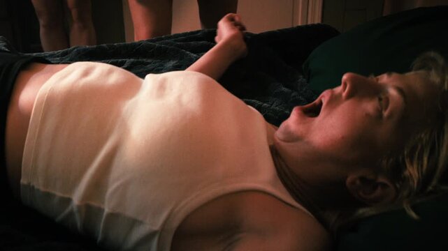 young woman writhes on bed during an exorcism