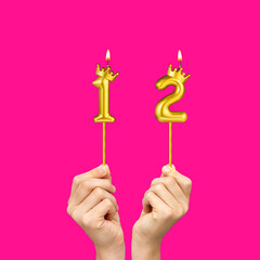 Birthday on a fuchsia background with the number 12 - Hands holding number-shaped candles
