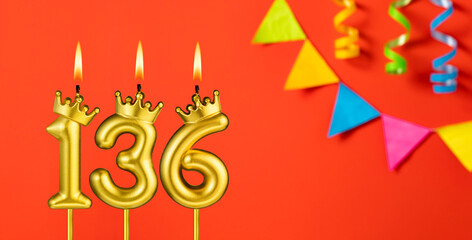 Number 136 birthday candle on an orange background with pennants