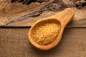 Organic brown sugar in a wooden spoon - Saccharum officinarum