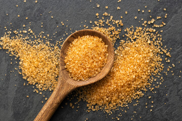 Saccharum officinarum - Organic brown sugar in a wooden spoon