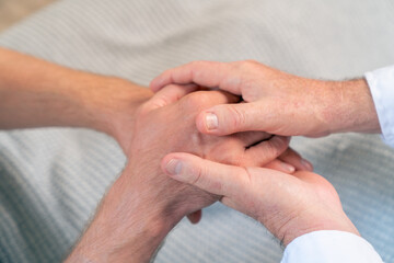 Doctor holding hands and comfort male patient. Medical health care, disease diagnosis and empathy communication support. Healthcare therapy, psychotherapy, wellness consultation in hospital clinic.