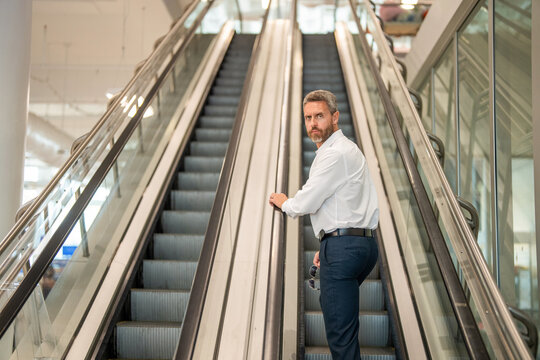 Businessman escalator in subway station. Man in business center, copy space. Man shopping mall. Airport business travel. International business trip. Metro train station. Airport terminal escalator
