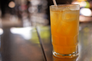 A glass of iced orange juiced with blurred background, A refreshing drink for hot weather