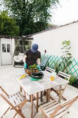 One man plants a flower in a pot in the backyard.