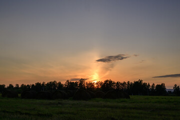 Sunset over a field with straw bales in the foreground