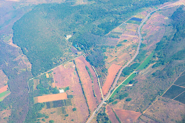 Aerial view of rural landscape with dense forests, open fields, and a winding road cutting through....