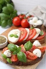 Tasty sandwiches with mozzarella cheese, tomatoes, basil and spices on light table, closeup