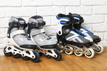 Roller skates on wooden table near white brick wall