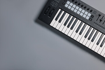 One portable MIDI keyboard on grey background, top view. Space for text