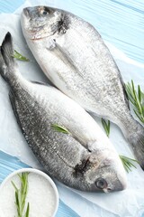 Fresh raw dourade with spices on blue wooden table, top view. Fish and seafood delicacies