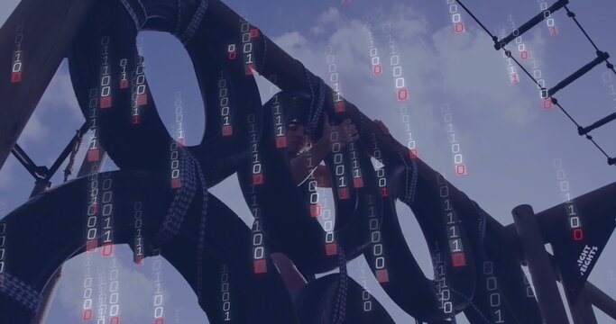 Climbing fit woman navigating tire obstacle course in park, featuring rope ladder and binary code