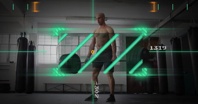 Holding loaded barbell shirtless man preparing deadlift in gym, with punching bags and AR overlay