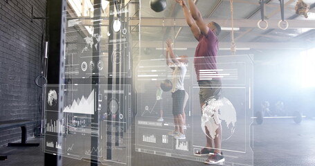 Man in purple tee slamming overhead medicine balls in gym with HUD overlays, rings, copy space