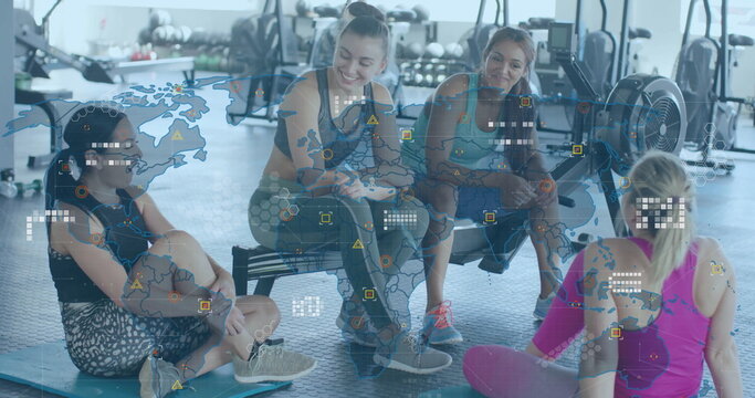 Resting group of four women chatting in gym environment, with kettlebells and world map overlay