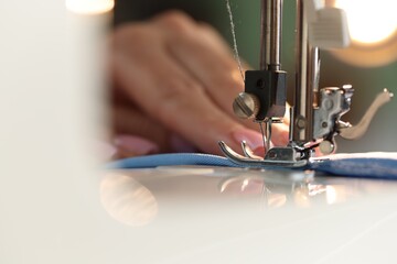 Woman working with sewing machine on blurred background, macro view