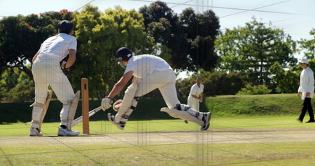 Diving batsman in white kit stretching bat toward crease on cricket pitch, with wooden stumps
