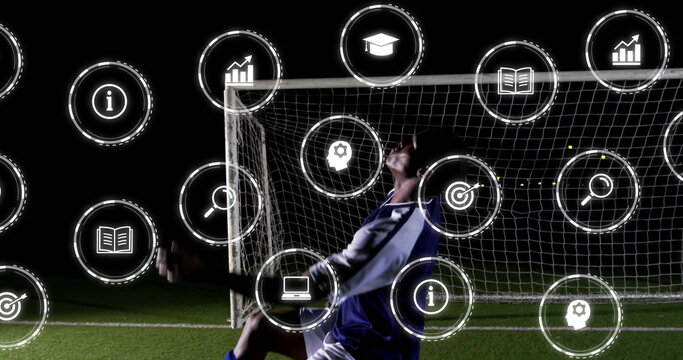 Diving soccer player wearing blue kit saving goal on night pitch, with digital icons