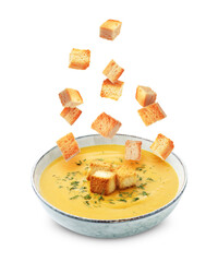 Croutons falling into bowl of soup against white background