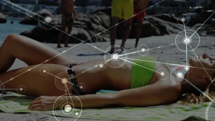 Female sunbather reclining demonstrating technology nodes expanding while man kicks soccer ball - Powered by Adobe