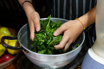 Hands grabbing fresh spinach to put it in the blender
