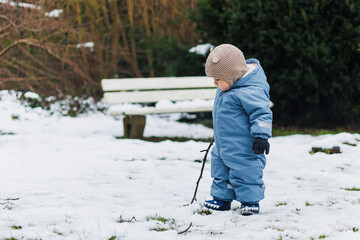 A Little Explorer immersing themselves in a magical Winter Wonderland A joyful child blissfully enjoying snowy outdoor adventures while playing with a stick in the frosty landscape