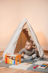 An adorable little baby is having a delightful time exploring their play tent, surrounded by...