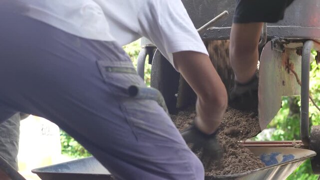 混ぜ合わせた土を運ぶ男性