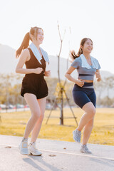 Two young women in exercise clothes are walking together, jogging together in the park.