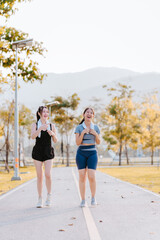 Two young women in exercise clothes are walking together, jogging together in the park.