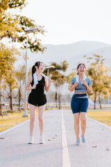 Two young women in exercise clothes are walking together, jogging together in the park.