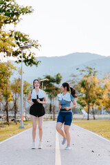 Two young women in exercise clothes are walking together, jogging together in the park.