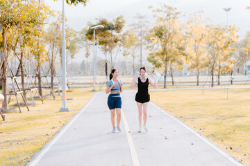 Two young women in exercise clothes are walking together, jogging together in the park.