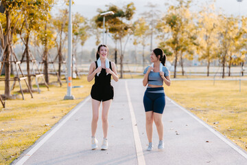 Two young women in exercise clothes are walking together, jogging together in the park.
