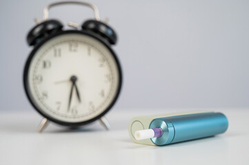 Electronic cigarette and alarm clock on white background. Tobacco heating systems.