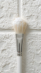 White Cosmetic Brush Applying Product on Textured White Tile Background