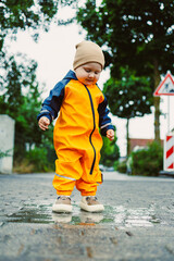A charming and lively toddler, dressed in a bright yellow rain suit, is having the time of their...