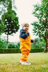 Fototapeta premium A joyful child in colorful rain gear explores a lively park, enjoying outdoor adventures in a place where creativity and imagination flourish, adding to the fun of this picturesque scene