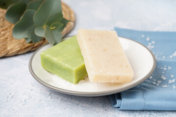 Plate with natural soap bars and eucalyptus branch on light background
