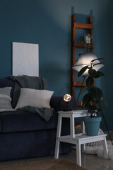 Interior of dark living room with blue sofa and glowing lamps