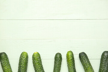 Fresh cucumbers on green wooden background