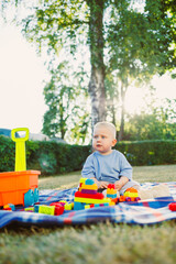 An adorable toddler is happily playing outdoors in a sunlit park, joyfully surrounded by colorful...